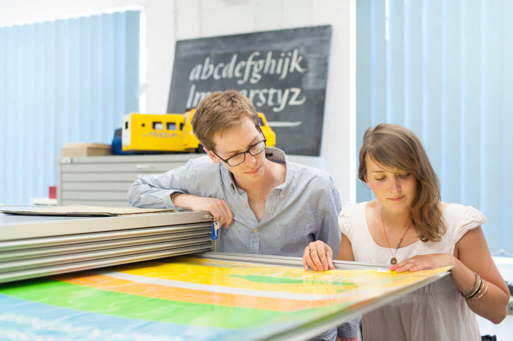 Two postgraduate students looking at historic posters in our Collections