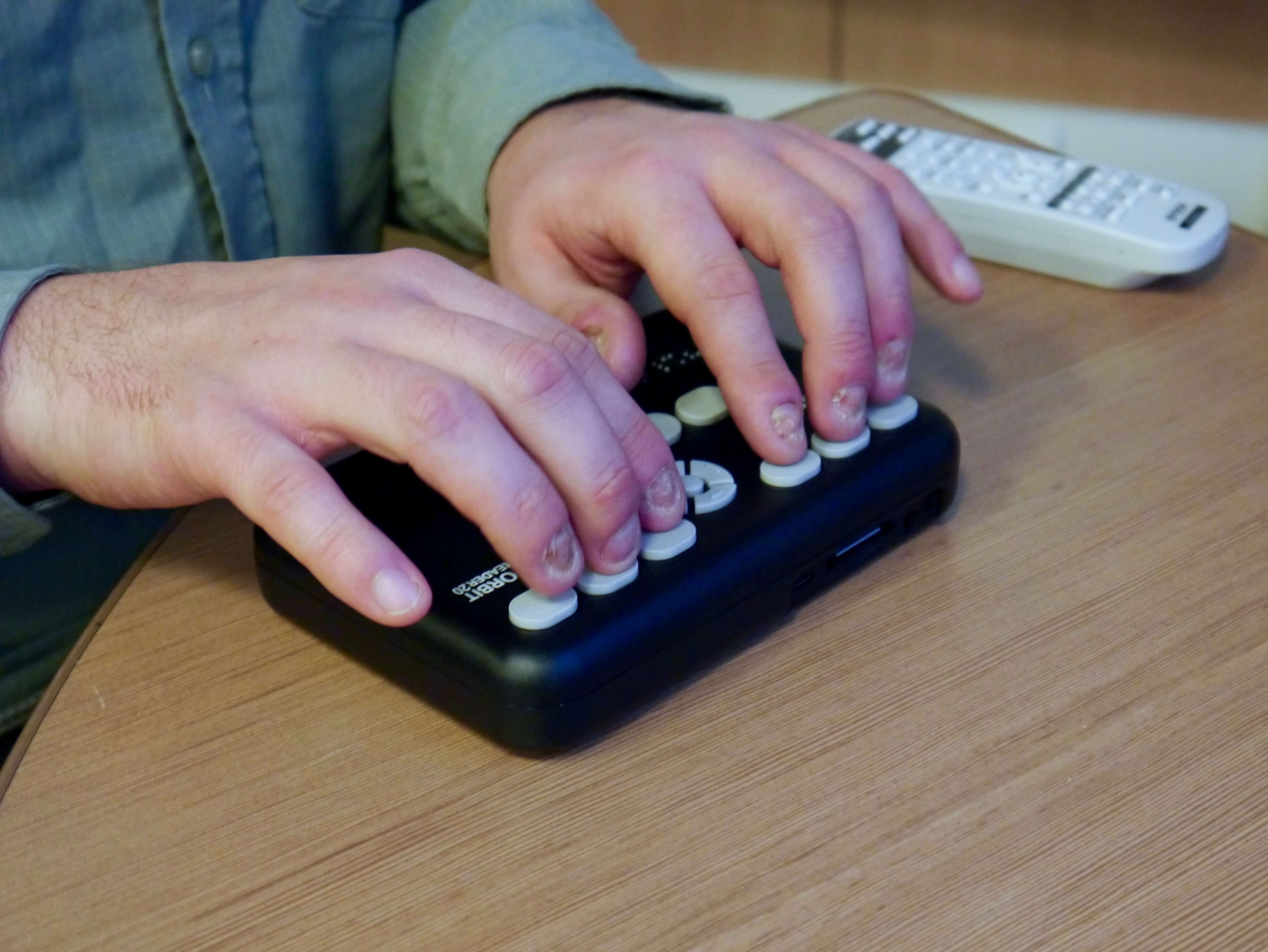 Photograph of the Orbit 20 reader in use on a table in the Reading Braillist's meeting