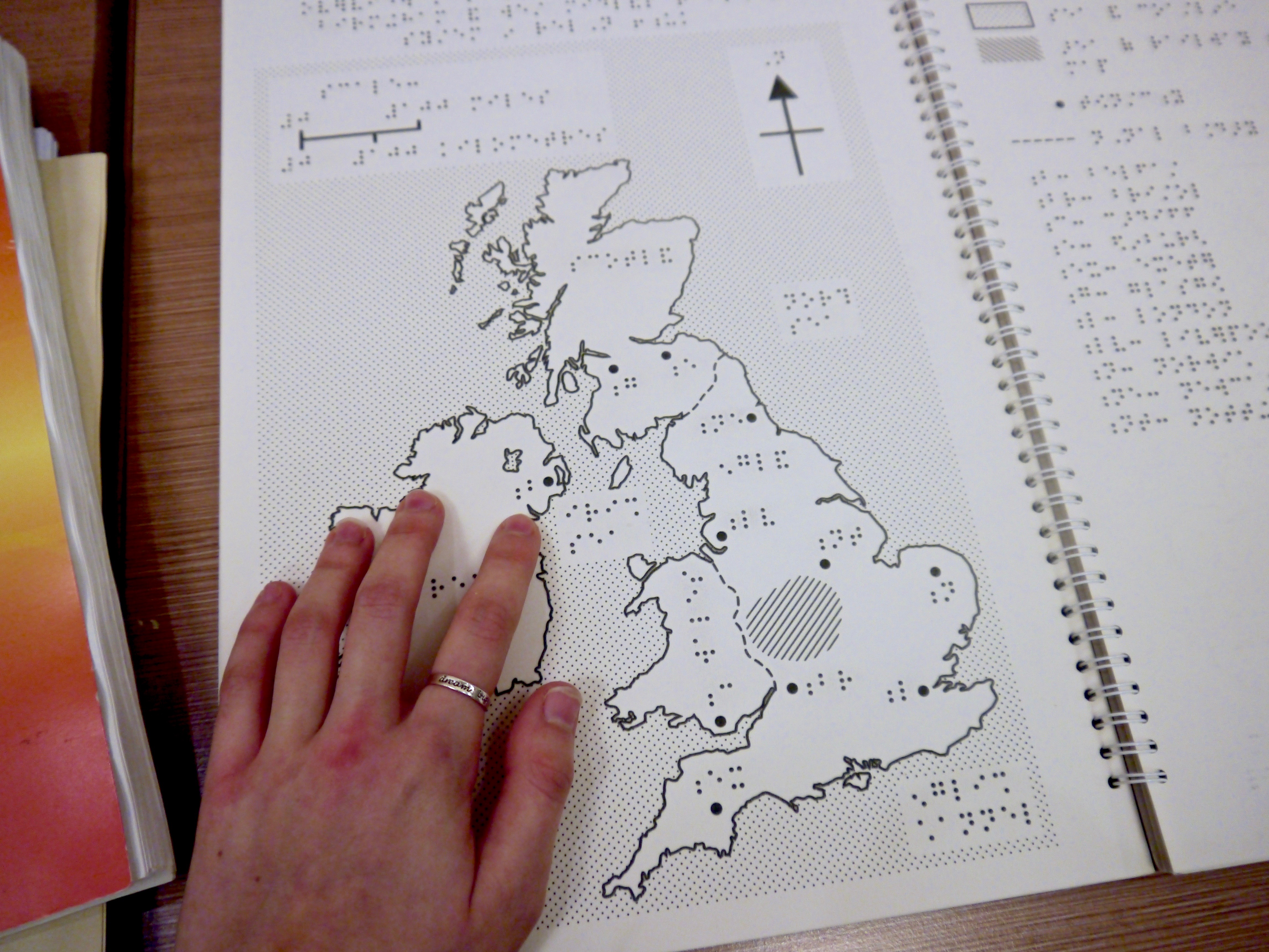 A photograph of a Braille map of the UK, being touched by a hand