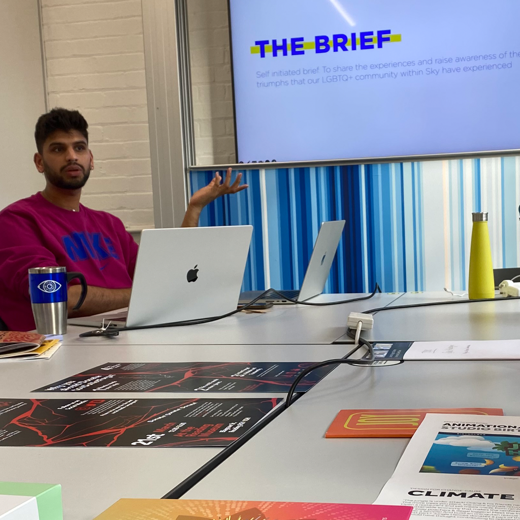 A person pointing towards a screen with the text 'The brief: Self initiated brief to share the experiences and raise awareness of the triumphs that our LGBTQ+ community within Sky have experienced'