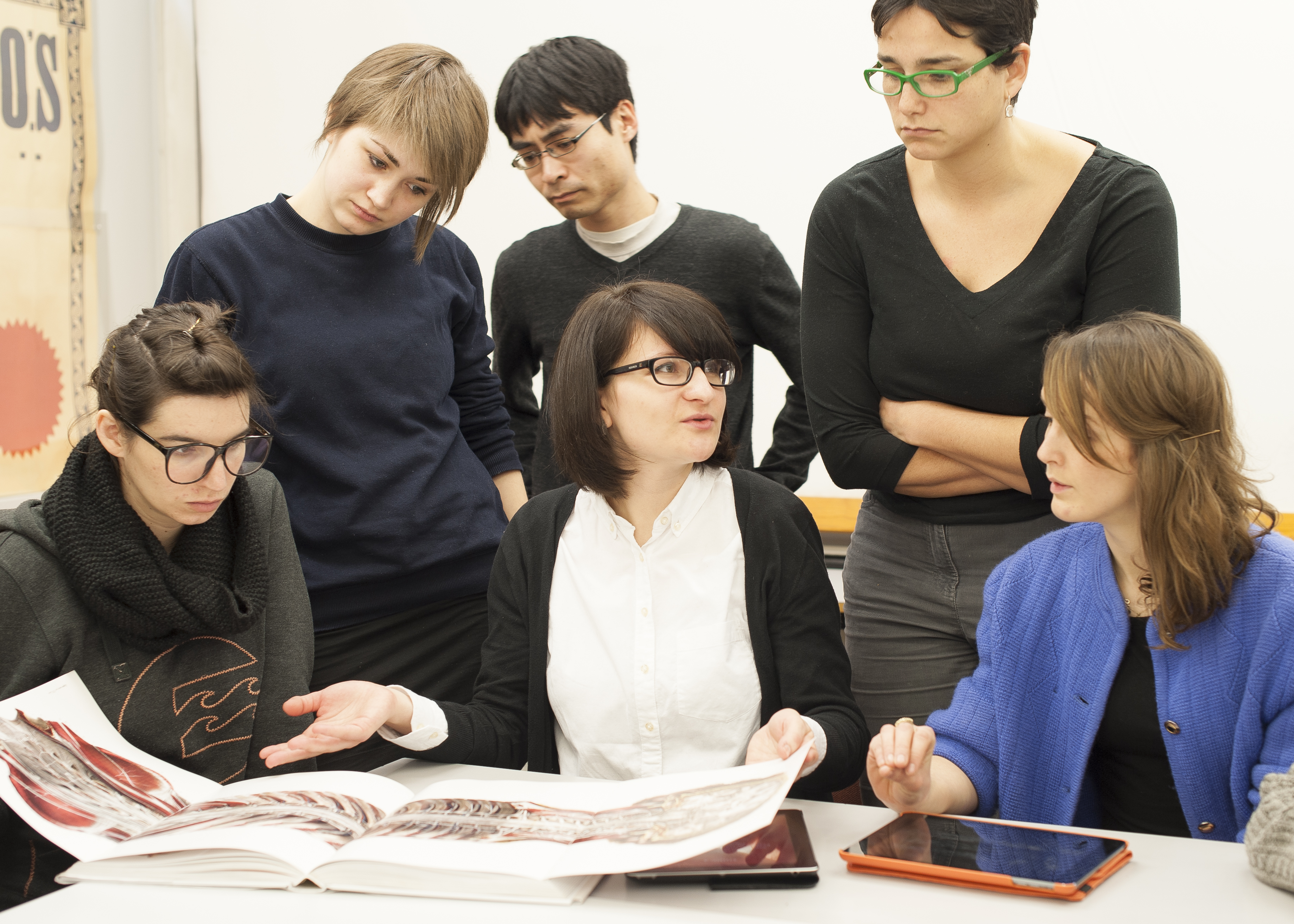 A group of five postgraduate students with a tutor looking at publishing projects