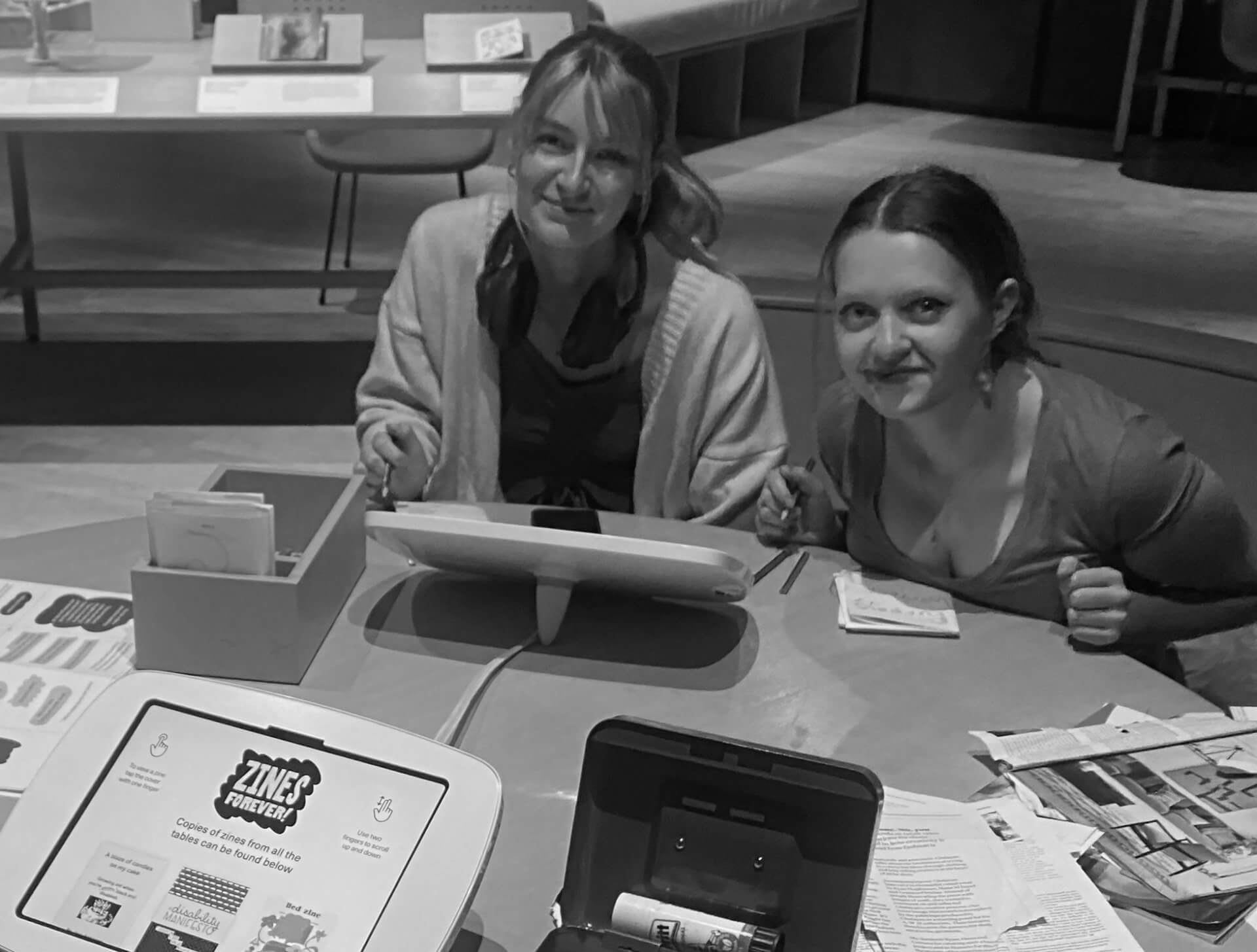 Two students sitting at a desk making zines