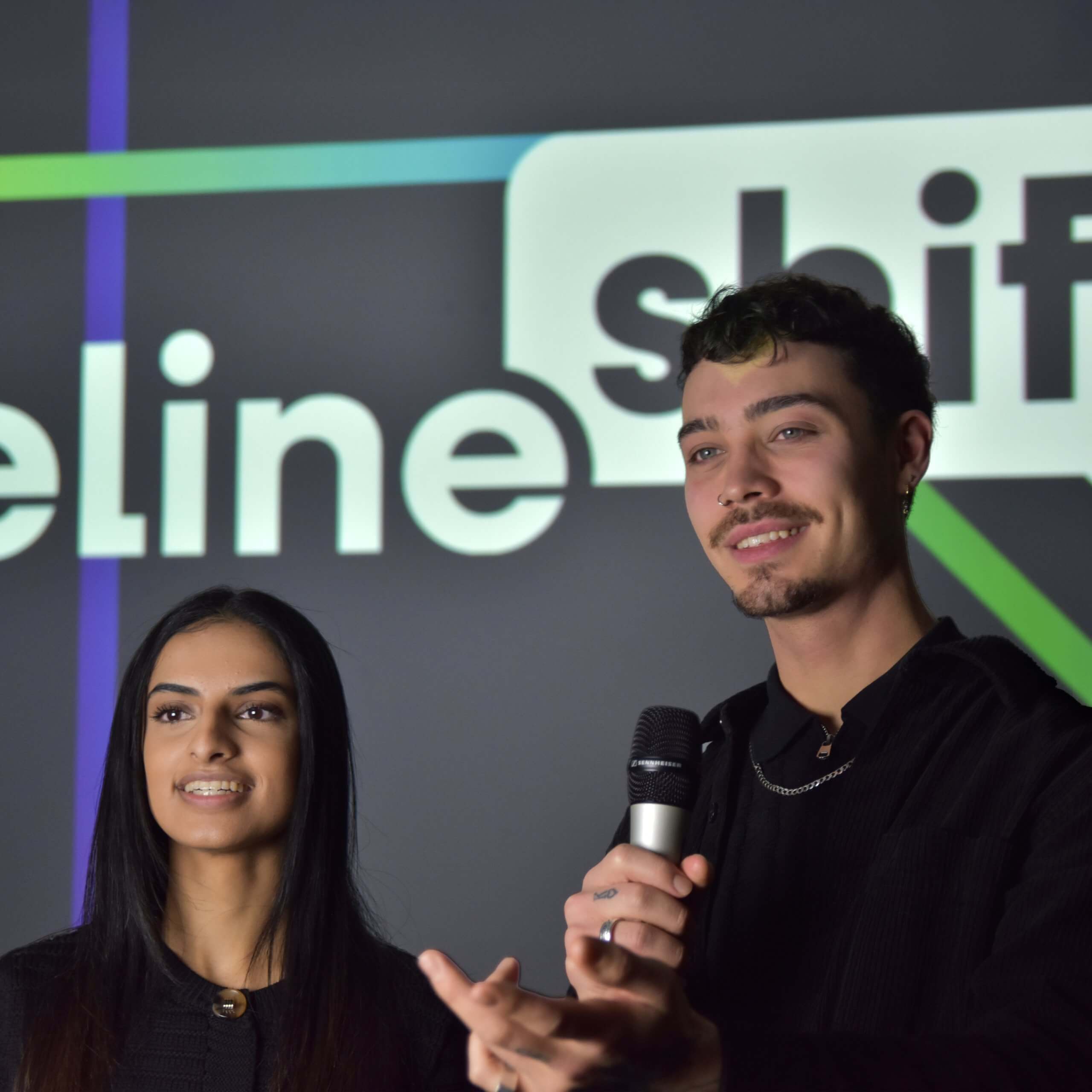 Tommy and Amirah presenting a Baseline Shift talk in front of the Baseline Shift logo
